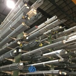 Wide view of metal pipes stacked in an industrial warehouse, emphasizing storage and organization.