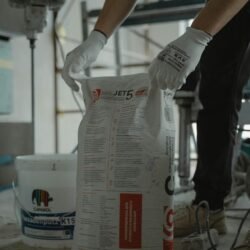 Worker handling cement bag in an indoor renovation project, wearing gloves for safety.