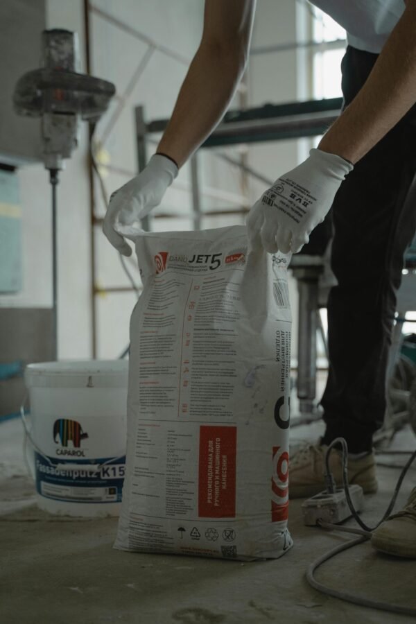 Worker handling cement bag in an indoor renovation project, wearing gloves for safety.